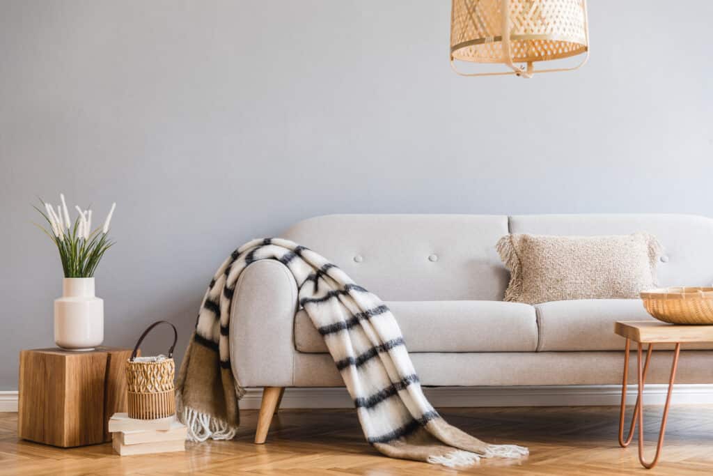 Décoration Salon Scandinave Beige avec Bois Clair Salon scandinave avec canapé beige, jeté à carreaux blanc et noir, et une lampe en bambou suspendue au-dessus.