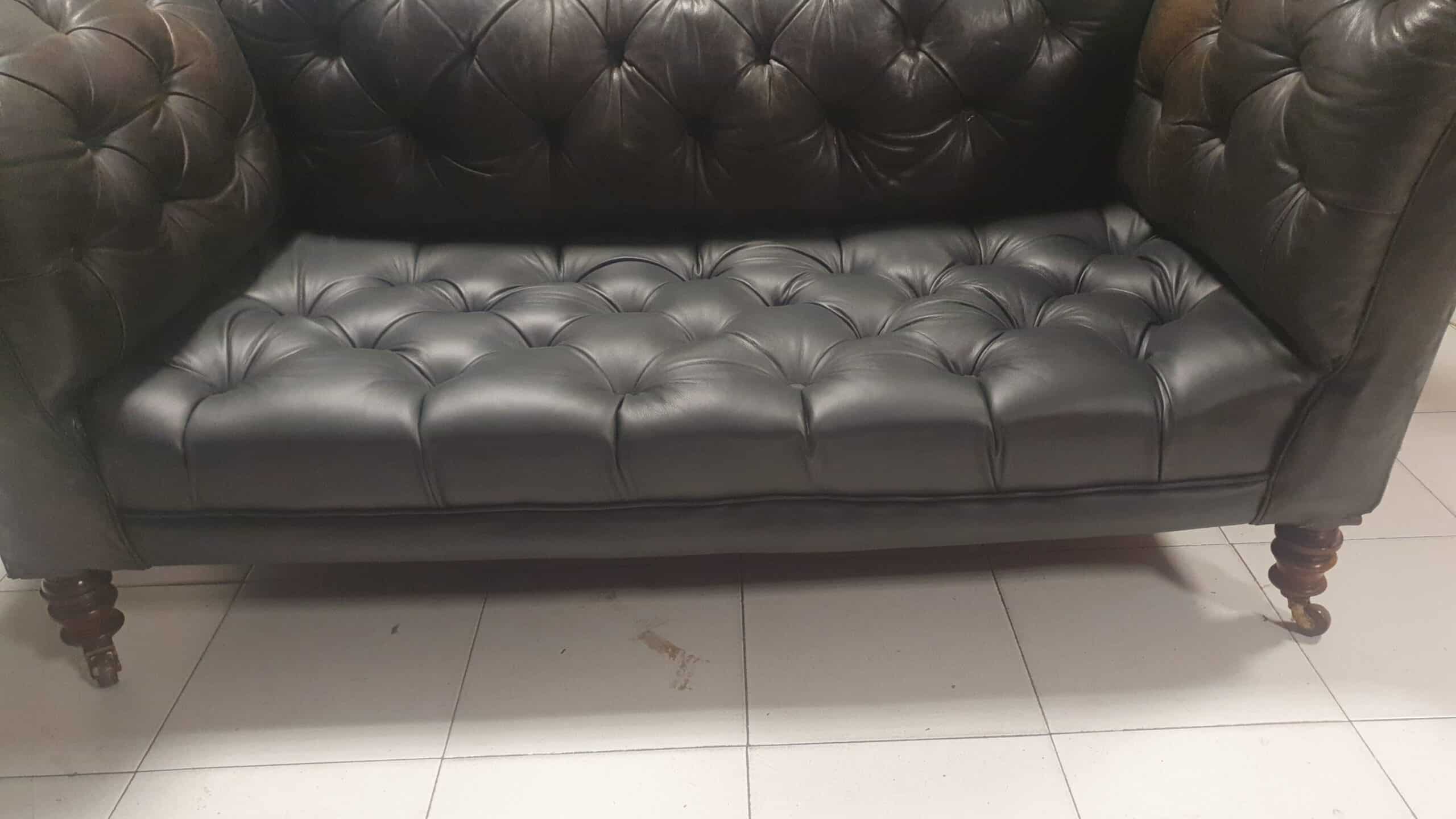 Canapé Chesterfield en cuir marron foncé capitonné avec pieds en bois sculptés sur roulettes.